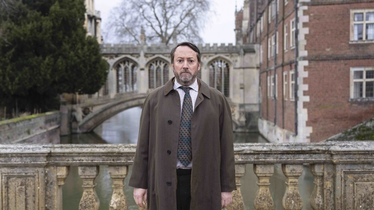 David Mitchell wearing a mac and standing on a bridge in Cambridge for BBC crime comedy Ludwig